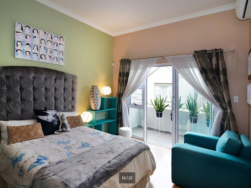 A well-lit bedroom featuring tiled flooring, an air conditioning unit, and a sliding glass door providing access to an outdoor balcony area.