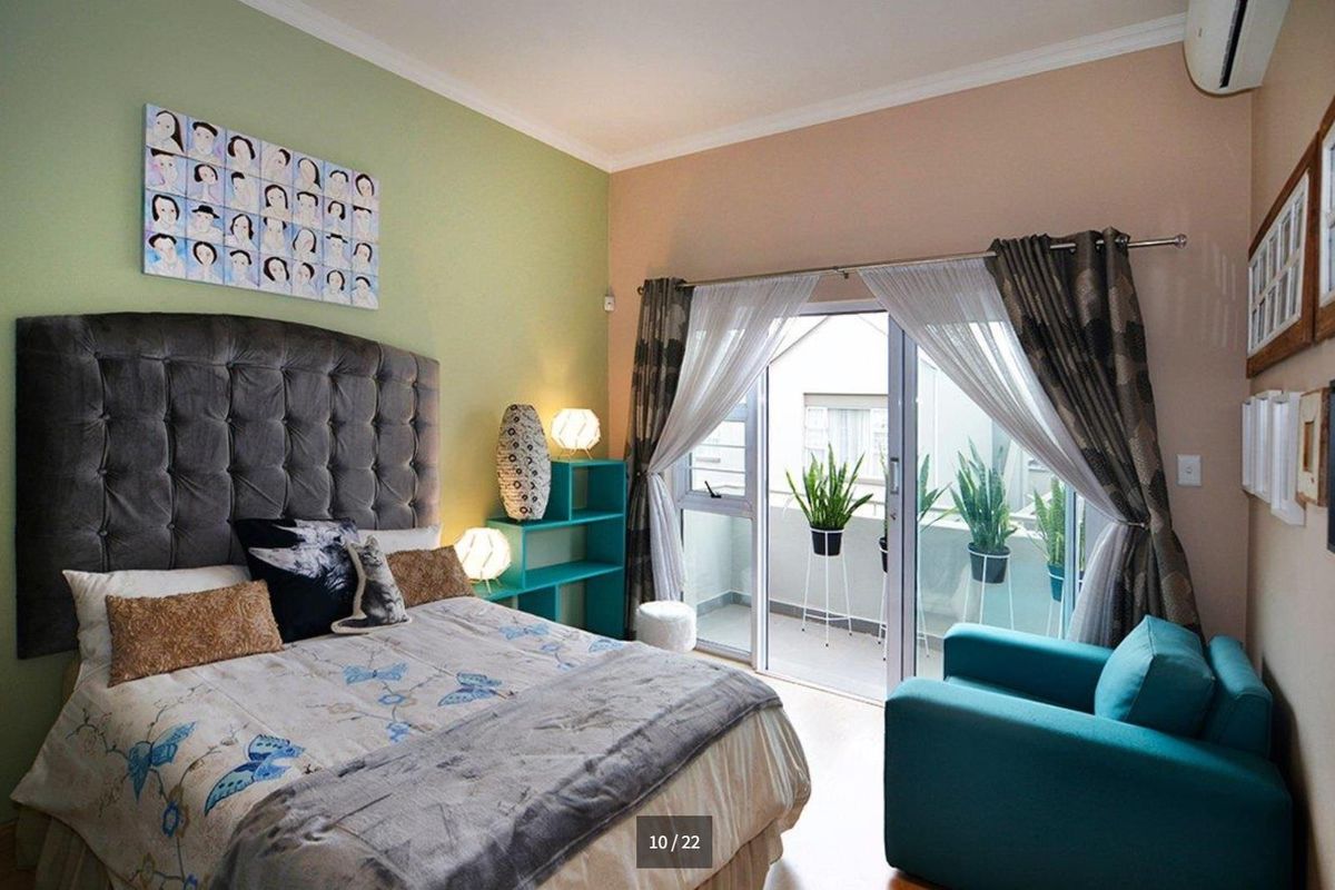 A well-lit bedroom featuring tiled flooring, an air conditioning unit, and a sliding glass door providing access to an outdoor balcony area.