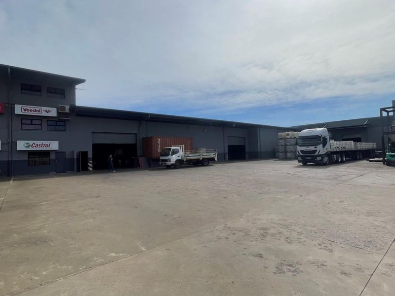 Spacious industrial yard area featuring multiple roller shutter access points, concrete paving, and commercial building frontage suitable for logistics or warehouse operations.
