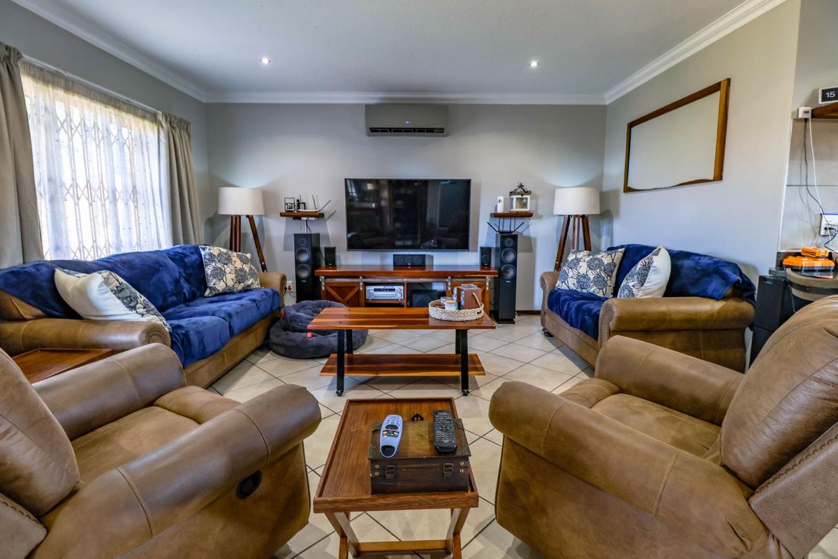 A well-maintained living room featuring tiled flooring, recessed downlighting, and a wall-mounted air conditioning unit, providing a comfortable and functional space.