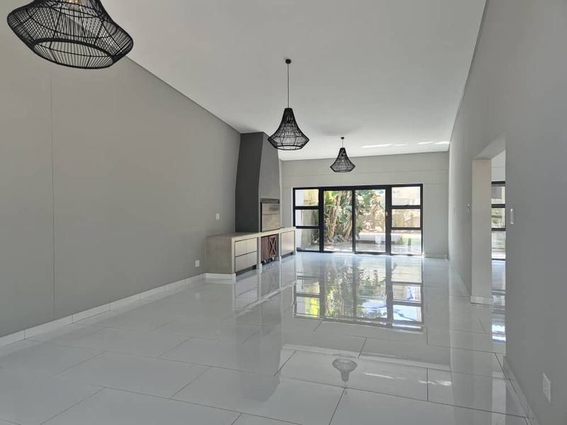 Spacious open-plan living area featuring polished tile flooring, a modern built-in fireplace, and large sliding glass doors leading to the garden.