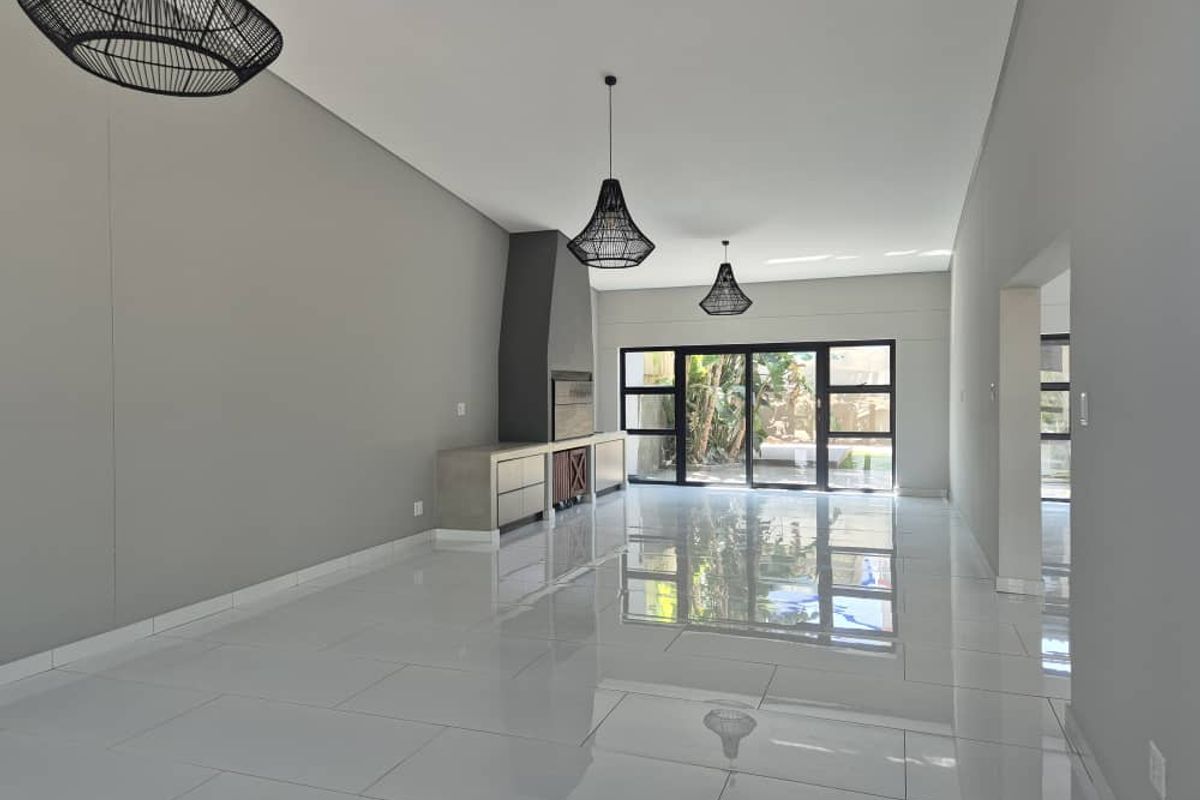 Spacious open-plan living area featuring polished tile flooring, a modern built-in fireplace, and large sliding glass doors leading to the garden.