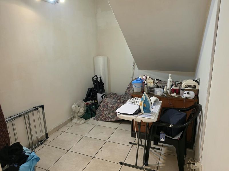 A utility space located under a staircase, featuring tiled flooring and neutral wall finishes, suitable for storage or a small workspace.