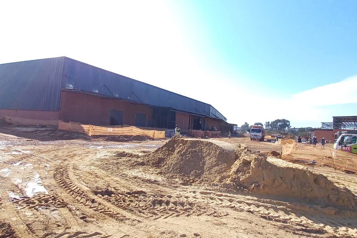 Wide view of an industrial property under construction, featuring large metal-clad warehouse structures and extensive site earthworks.