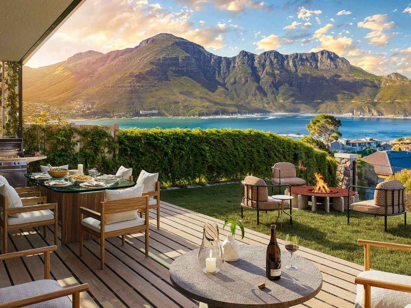 Spacious outdoor patio featuring timber decking, a built-in barbecue area, and a landscaped garden with stunning panoramic mountain and bay views.