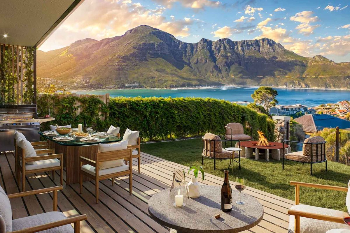 Spacious outdoor patio featuring timber decking, a built-in barbecue area, and a landscaped garden with stunning panoramic mountain and bay views.
