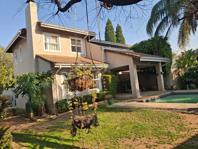 Rear view of the cluster property featuring a covered patio, swimming pool, and established garden area with a tiled roof and chimney.