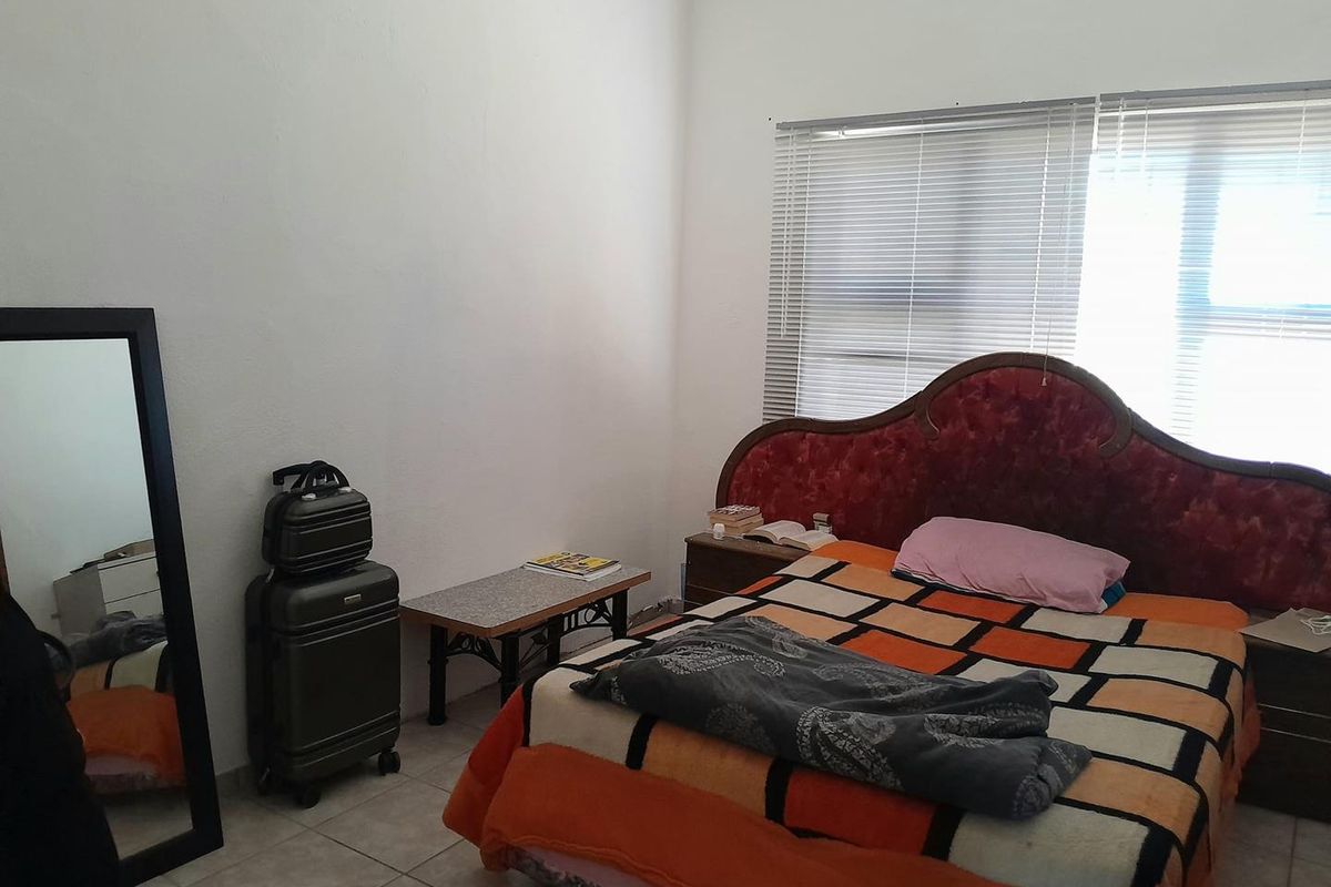 A bedroom featuring tiled flooring and horizontal window blinds, providing a functional space for rest.