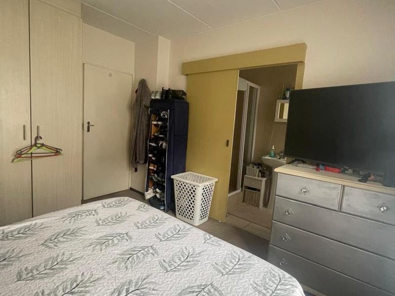 A bedroom featuring built-in cupboards and direct access to an en-suite bathroom, providing a functional layout with standard finishes.