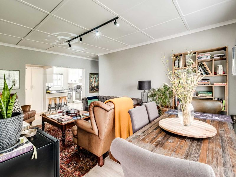 Open plan living and dining area featuring a tiled ceiling, track lighting, and a view through to the functional kitchen space.