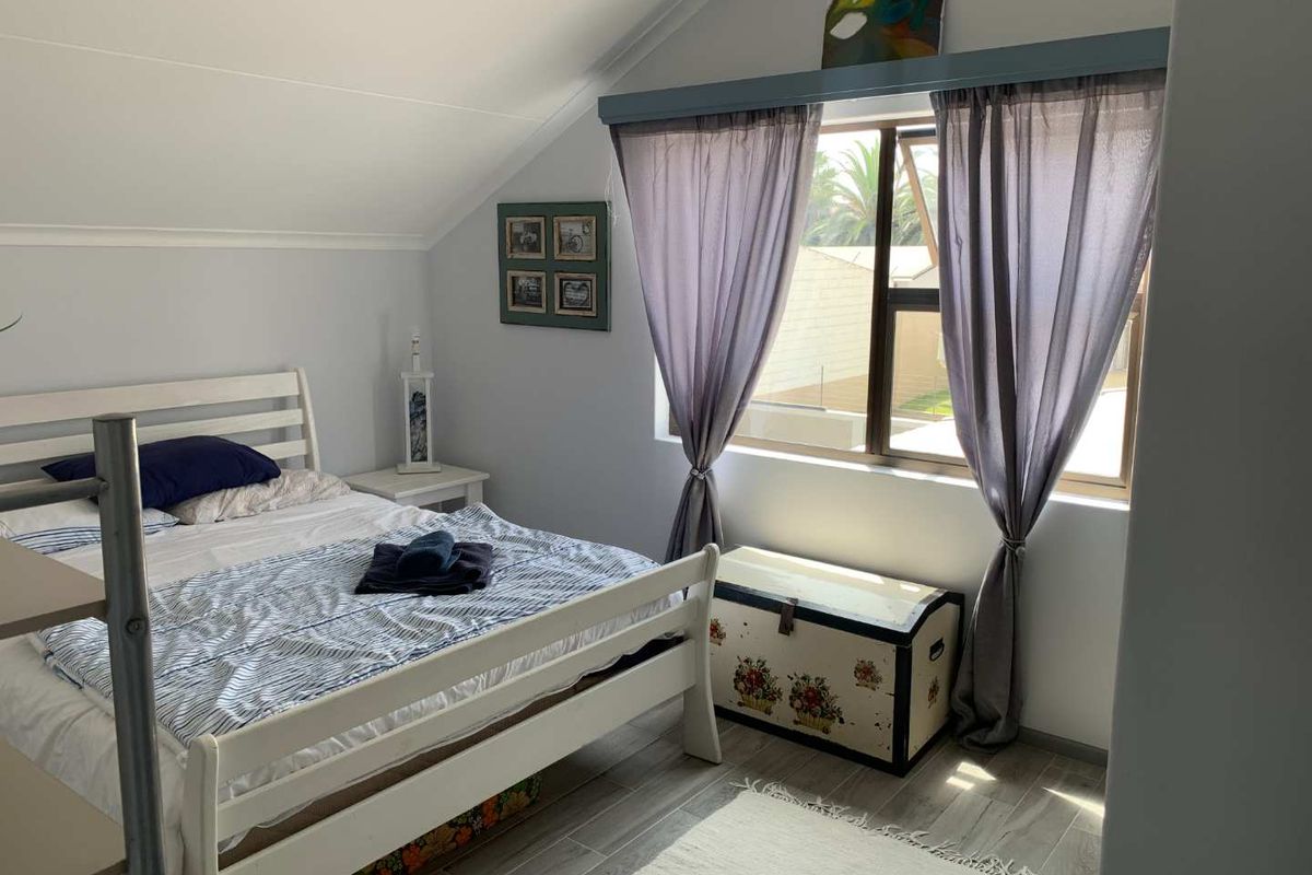 A cozy bedroom featuring a sloped ceiling, tiled flooring, and a window that allows for natural light.