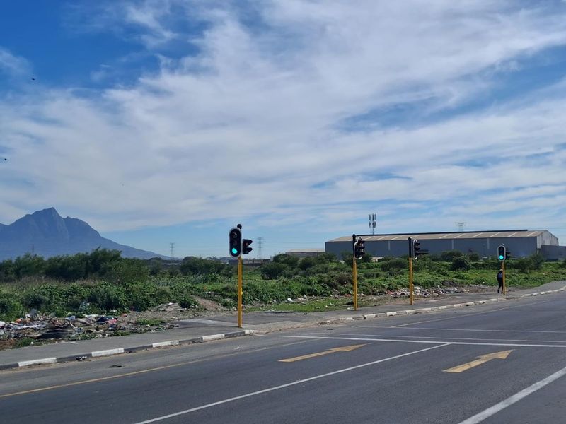 Street view of the agricultural land showing adjacent road infrastructure, traffic lights, and surrounding landscape with mountain views.