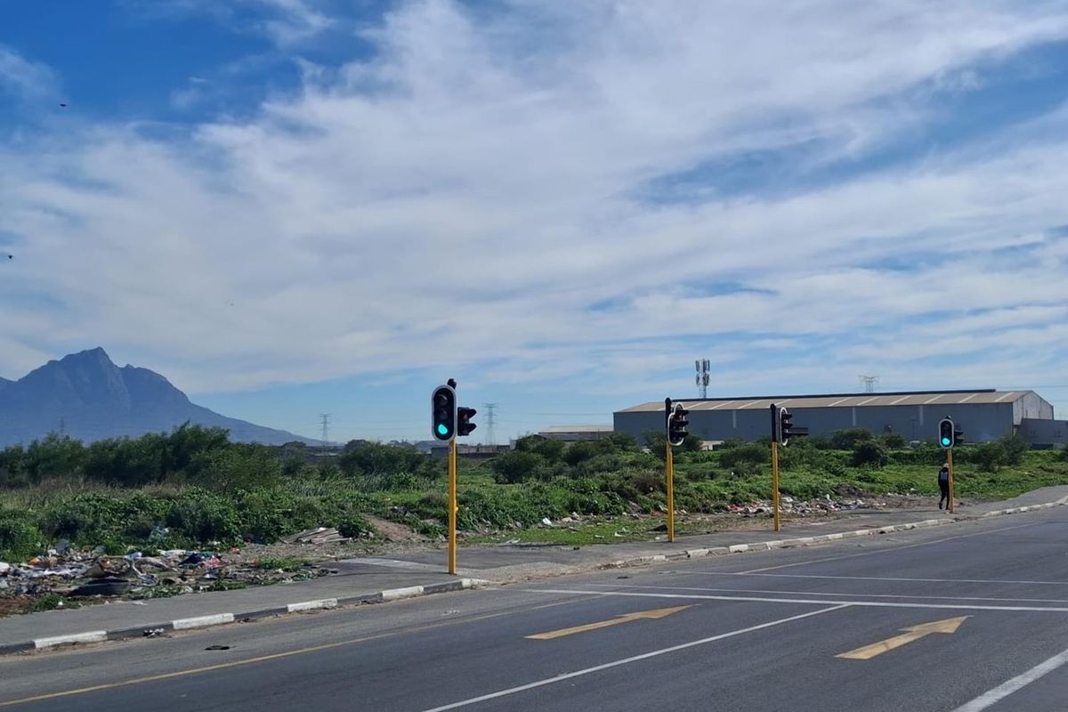 Street view of the agricultural land showing adjacent road infrastructure, traffic lights, and surrounding landscape with mountain views.