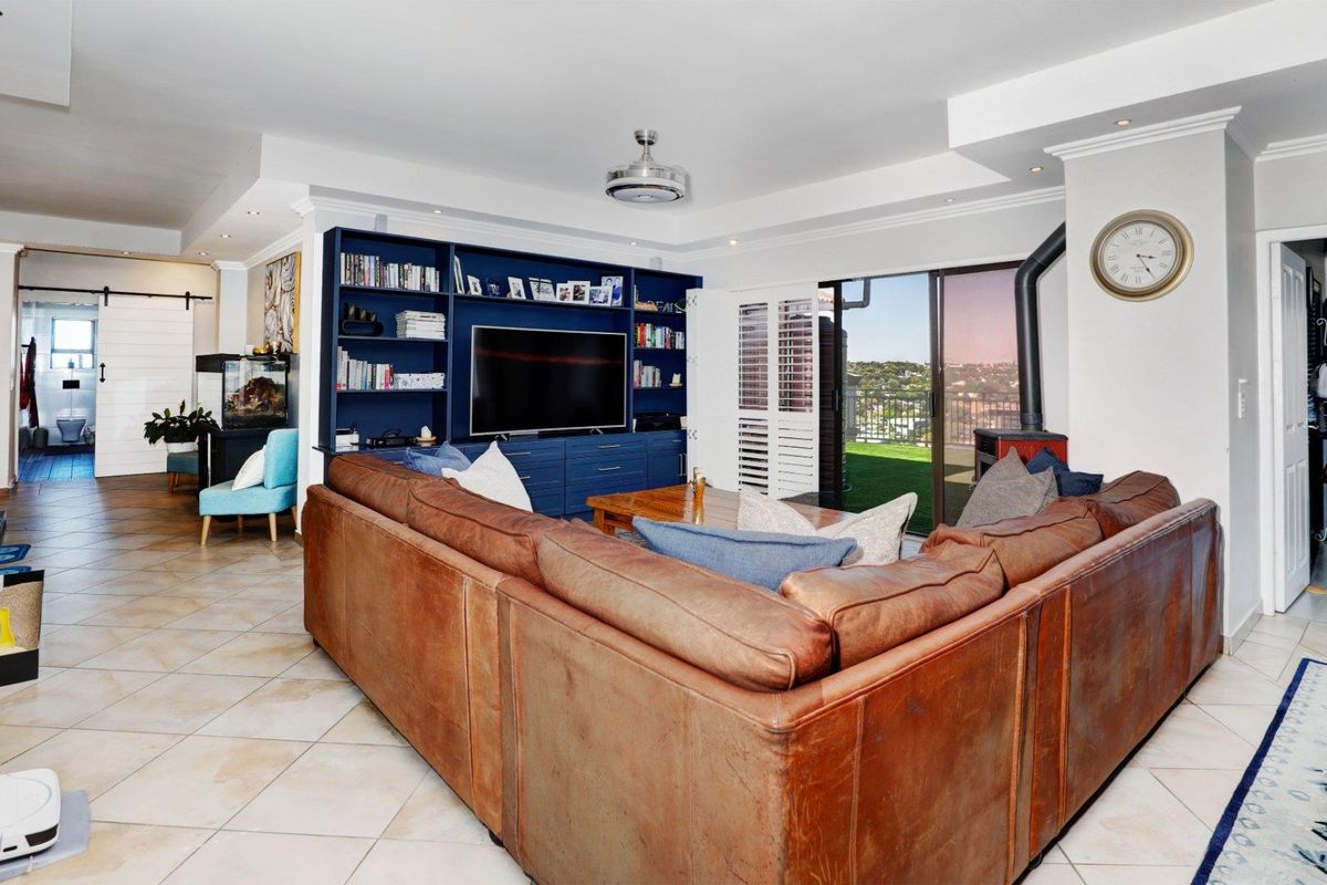 Spacious living area featuring a built-in blue media unit, a freestanding fireplace, and sliding glass doors leading to an outdoor balcony.