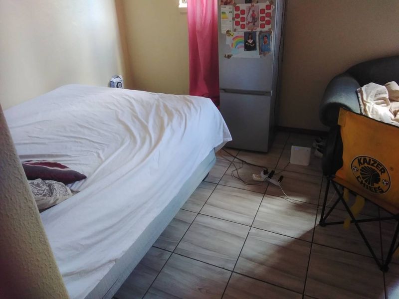 A bedroom featuring tiled flooring and neutral wall finishes, providing a functional living space.