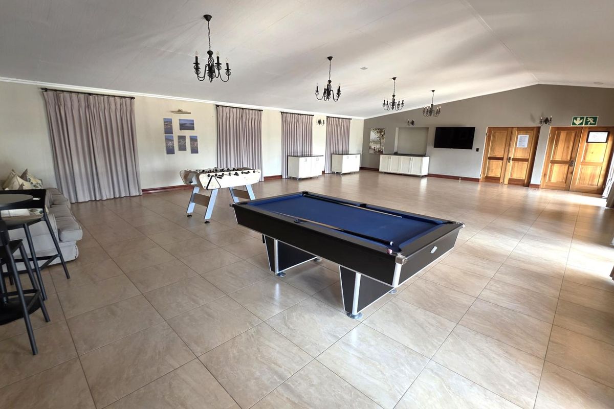 Spacious entertainment area featuring tiled flooring, multiple chandeliers, and built-in cabinetry, suitable for a games room or large social gathering space.