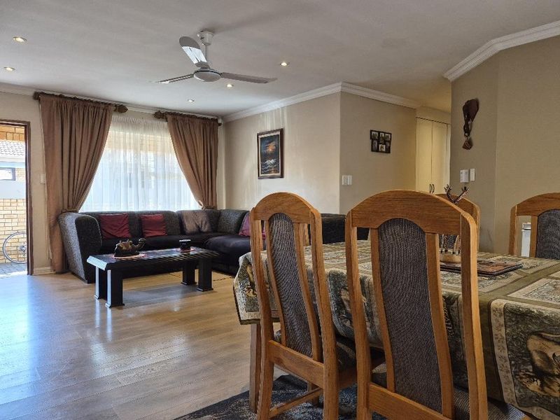 Spacious open-plan living and dining area featuring laminate flooring, recessed lighting, and a ceiling fan, creating a comfortable and functional living space.
