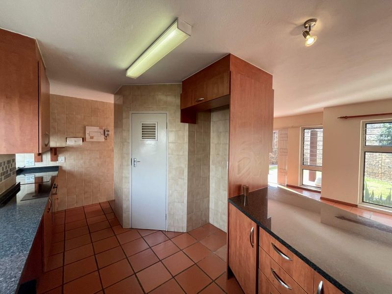 A functional kitchen featuring built-in wooden cabinetry, granite countertops, and tiled flooring, offering a clean and practical layout for renovation.