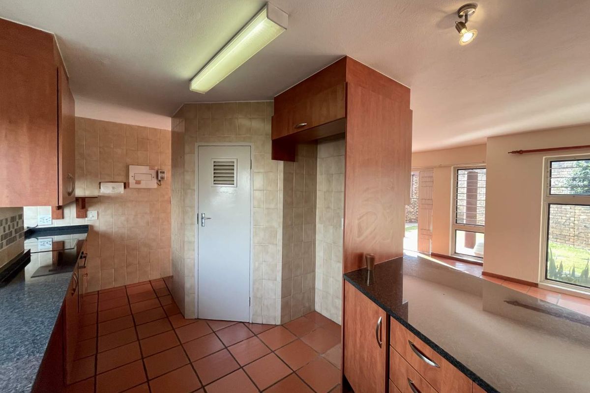 A functional kitchen featuring built-in wooden cabinetry, granite countertops, and tiled flooring, offering a clean and practical layout for renovation.