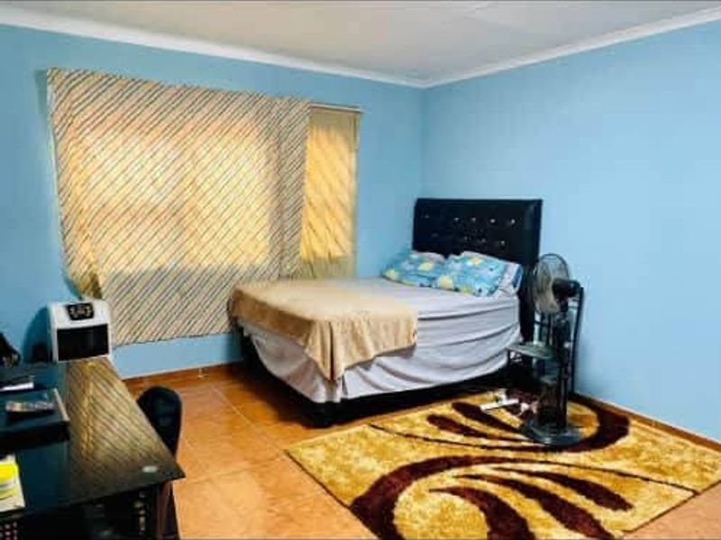 A standard bedroom featuring tiled flooring and blue painted walls, providing a functional sleeping space.