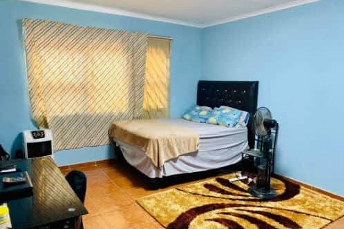 A standard bedroom featuring tiled flooring and blue painted walls, providing a functional sleeping space.