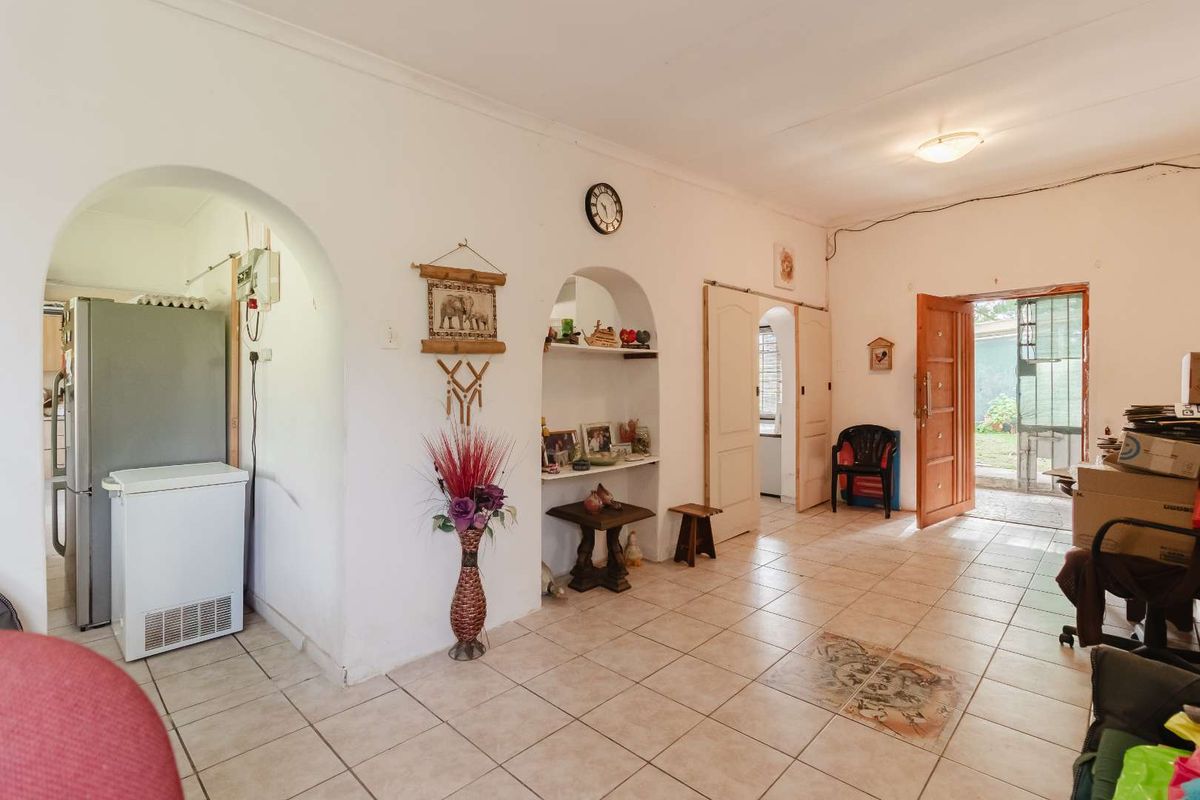 Living area featuring ceramic tiled flooring, arched architectural details, a built-in wall niche, and direct access to the exterior through a wooden door.