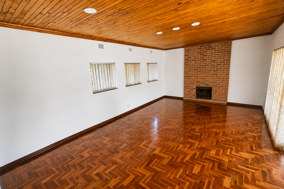 Spacious living room featuring polished herringbone parquet flooring, a classic brick fireplace, and a warm timber-paneled ceiling with recessed lighting.