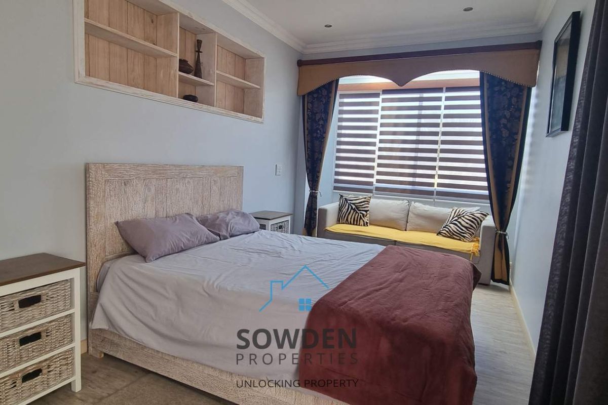 A well-maintained bedroom featuring built-in wooden shelving and modern window blinds, offering a comfortable and functional living space.