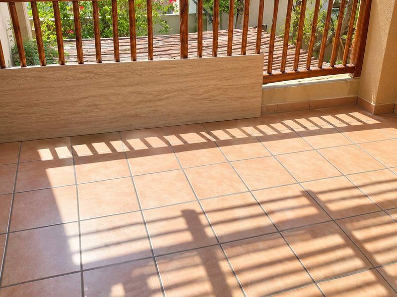 A covered balcony area featuring terracotta-style floor tiles and a wooden balustrade, offering a functional outdoor space.