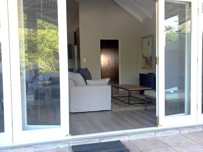 A covered patio area featuring stone tile flooring and double glass doors providing seamless access to the interior living space.