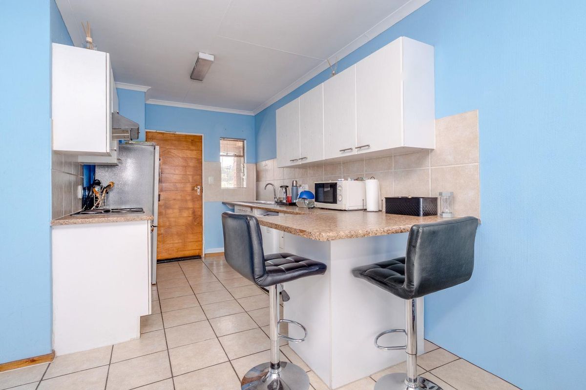A functional kitchen featuring laminate countertops, tiled backsplash, ceramic flooring, and built-in cabinetry with an integrated breakfast bar area.