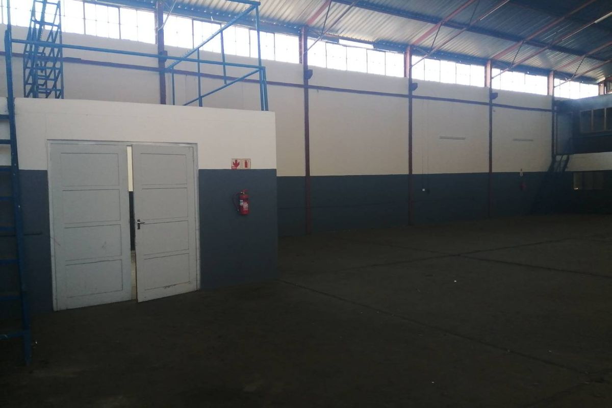 Spacious industrial warehouse unit featuring high ceilings with exposed steel trusses, clerestory windows for natural light, and concrete flooring.