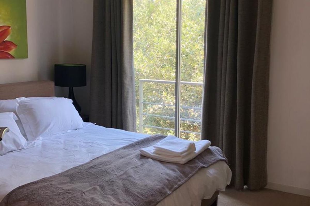 A comfortable bedroom featuring carpeted flooring, recessed lighting, and a sliding glass door that provides access to an outdoor balcony area.