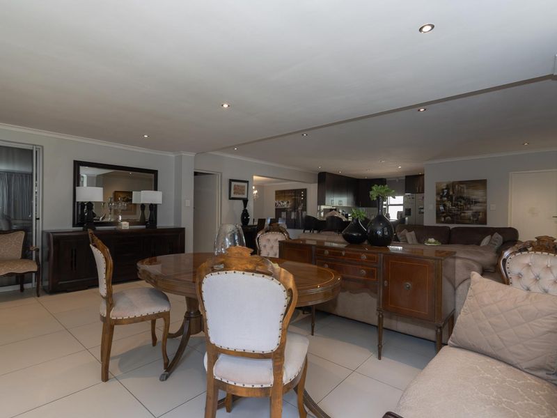 Spacious open-plan living and dining area featuring neutral tiled flooring, recessed lighting, and seamless flow into the adjacent kitchen space.