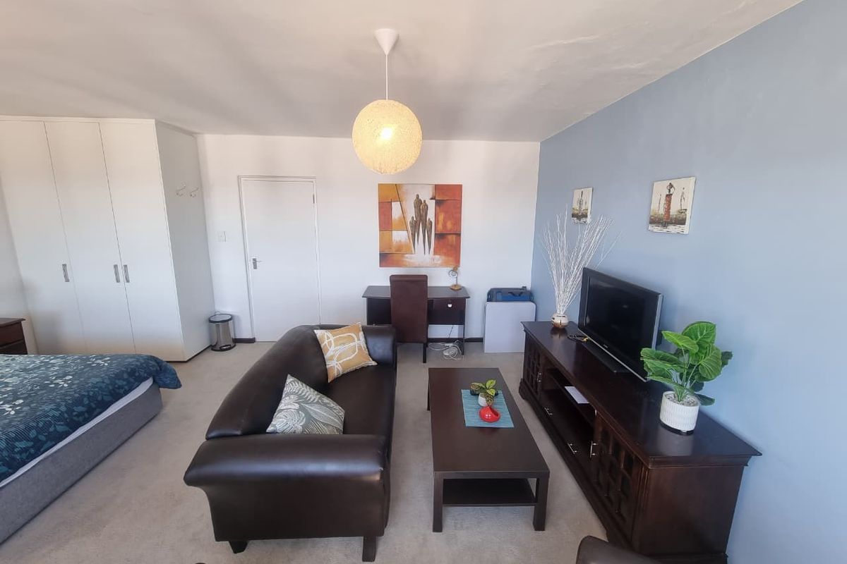 A spacious bedroom featuring built-in wardrobes, neutral carpeting, and a dedicated study nook, offering a functional and comfortable living space.