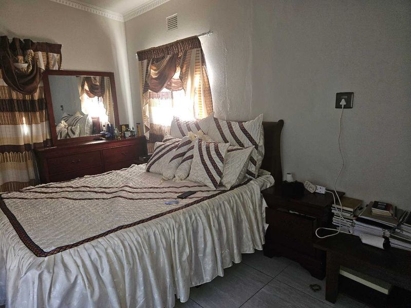 A bedroom featuring tiled flooring and decorative cornice, currently showing signs of wear on the wall surfaces.