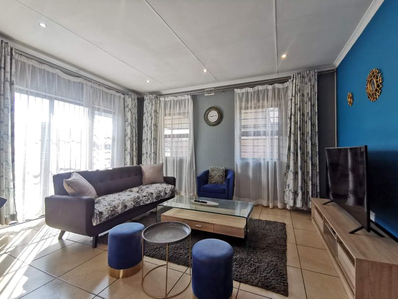 A bright and well-maintained living room featuring tiled flooring, recessed downlighting, and a large sliding glass door providing ample natural light.