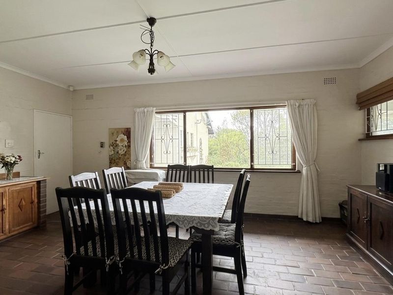 A dining room featuring brick flooring, built-in wooden cabinetry, and large windows with security bars, offering a functional and traditional living space.