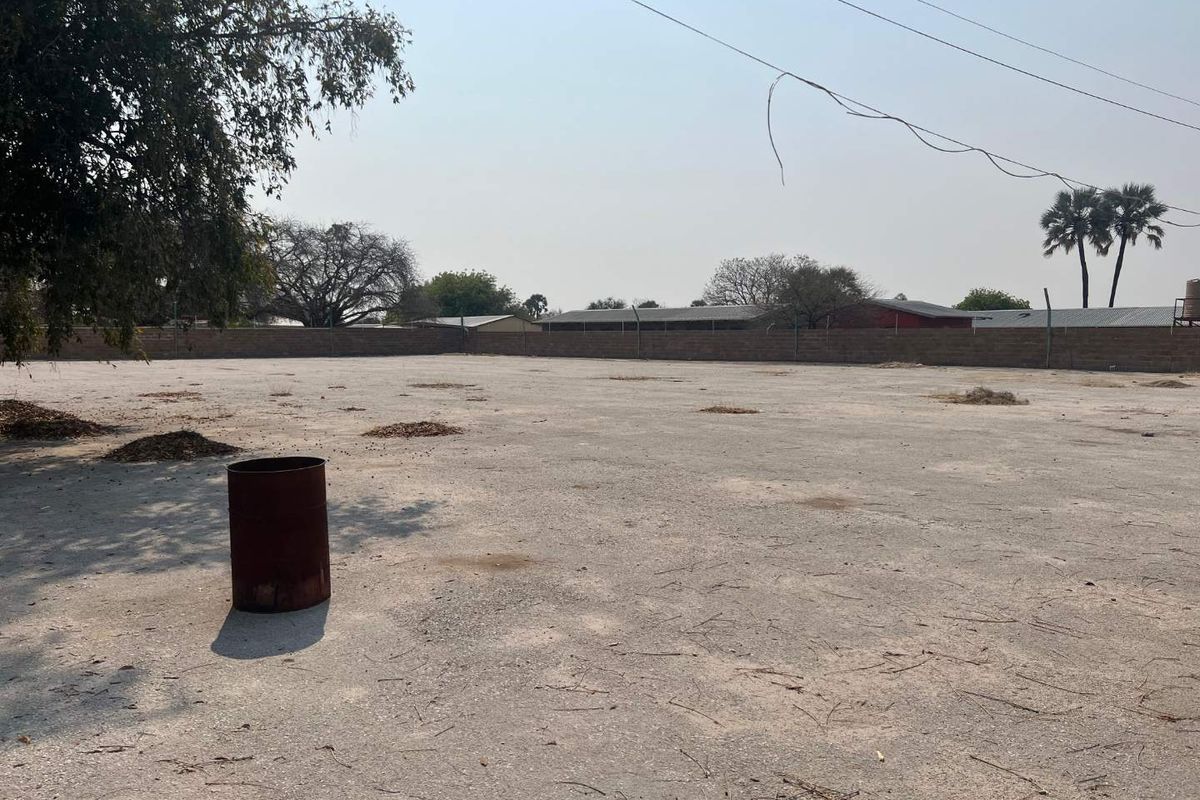 A large, open, paved outdoor area enclosed by a perimeter wall, suitable for development or storage use.