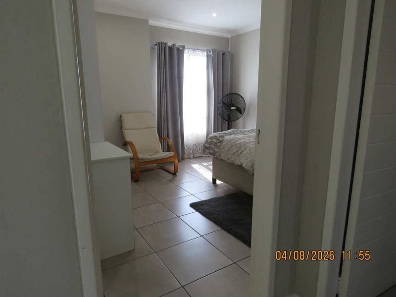 A bedroom featuring neutral tiled flooring and recessed ceiling lighting, viewed from the doorway.