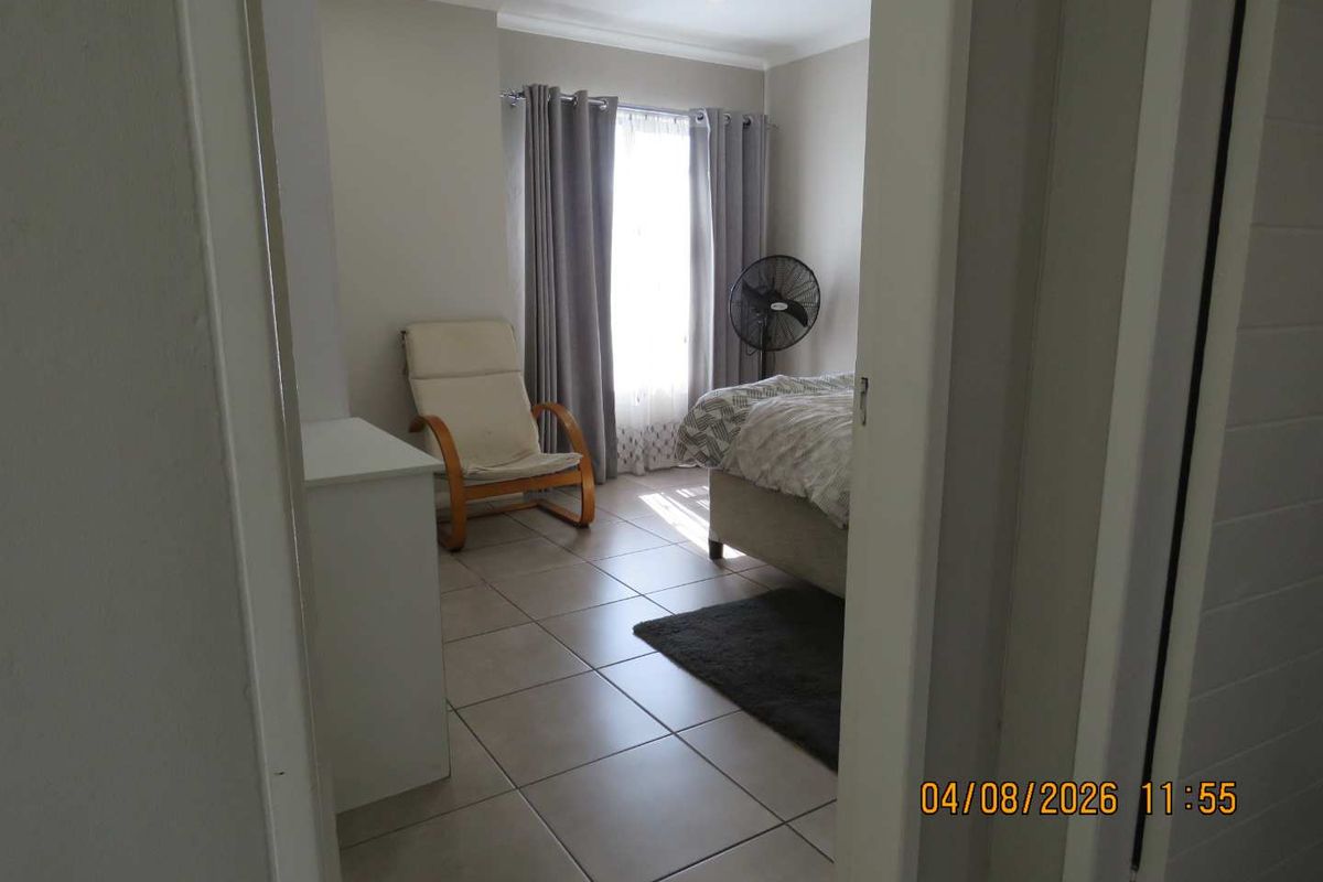 A bedroom featuring neutral tiled flooring and recessed ceiling lighting, viewed from the doorway.