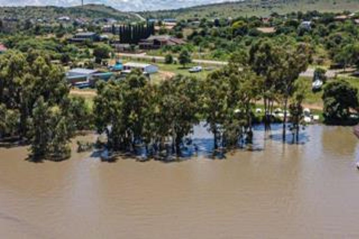 An aerial view of the residential land plot featuring mature trees and direct access to the adjacent river or water body.