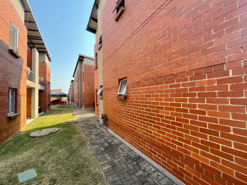 Exterior view of the apartment complex featuring exposed brick facades, a paved walkway, and landscaped lawn areas between the building blocks.