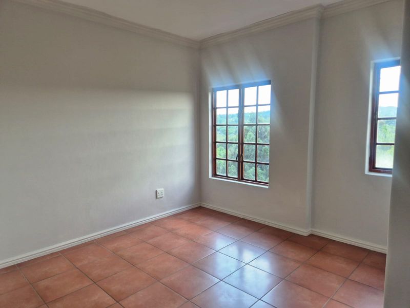 A bright, empty bedroom featuring terracotta floor tiles, wooden window frames, and neutral walls, offering a blank canvas for personalization.