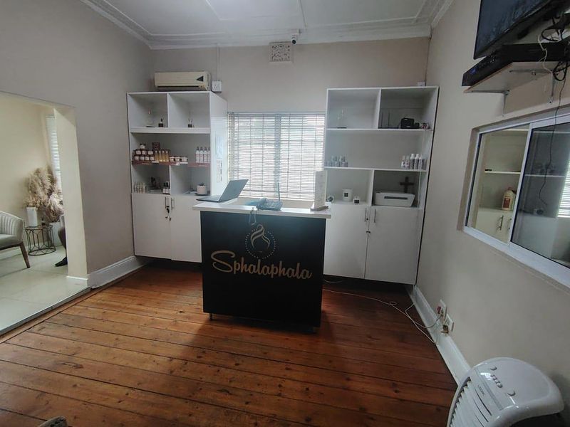 A functional office space featuring timber flooring, built-in storage shelving, and wall-mounted air conditioning, suitable for a reception or administrative area.