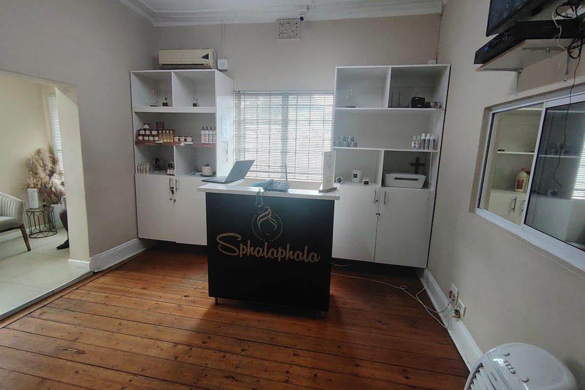 A functional office space featuring timber flooring, built-in storage shelving, and wall-mounted air conditioning, suitable for a reception or administrative area.