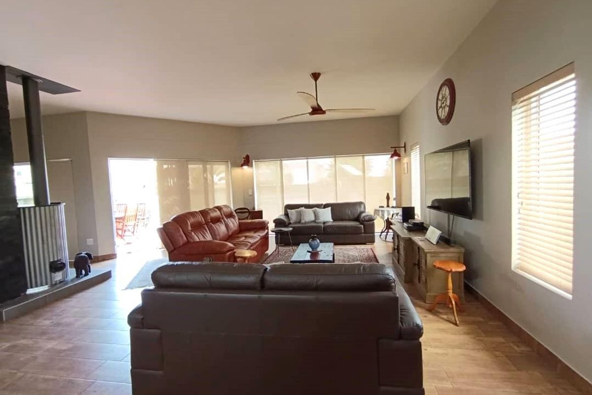 Spacious living area featuring tiled flooring, a built-in fireplace, ceiling fan, and large windows with blinds, offering a comfortable and functional layout.
