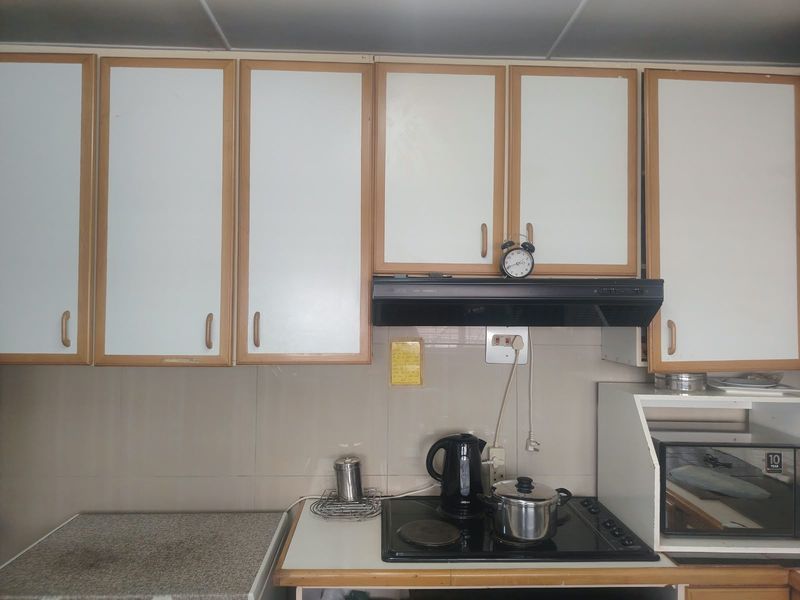 A functional kitchen area featuring built-in cabinetry, a tiled splashback, and an integrated electric hob with an overhead extractor fan.
