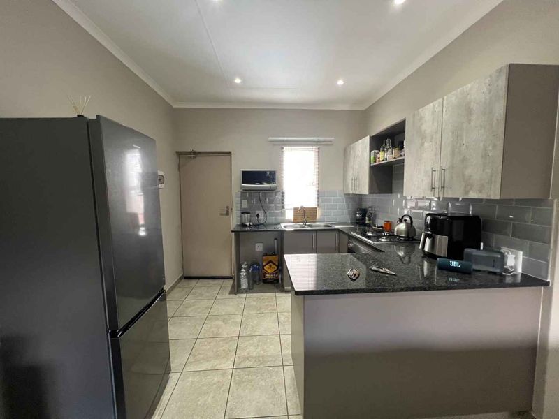 A functional kitchen featuring granite countertops, subway tile backsplash, ample built-in cabinetry, and tiled flooring, providing a clean and practical workspace.