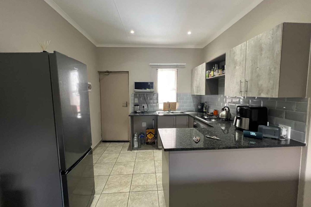 A functional kitchen featuring granite countertops, subway tile backsplash, ample built-in cabinetry, and tiled flooring, providing a clean and practical workspace.
